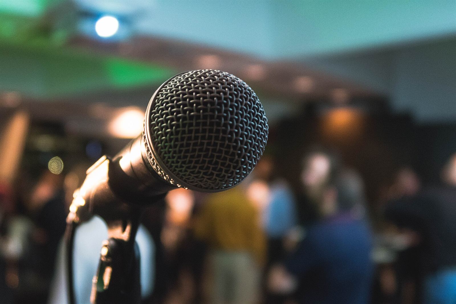 A microphone on stage with a busy room behind it